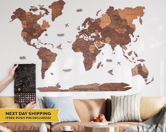 May include: A large wooden world map wall art piece featuring various shades of brown wood, with laser-cut continents and country names. The map includes decorative wooden icons of airplanes and ships, and is displayed with a box of colorful push pins.