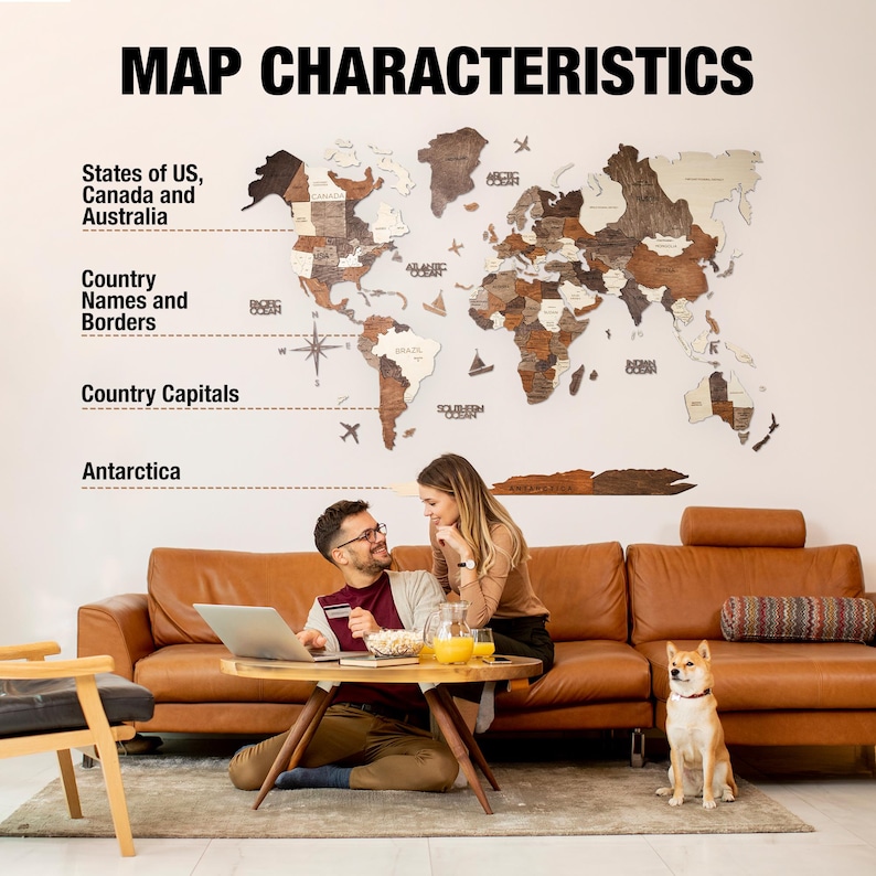 May include: A wooden world map with a light brown background and dark brown borders. The map shows the states of the US, Canada, Australia, and country names and borders. The map is hanging on a white wall in a living room with a brown leather sofa and a dog.