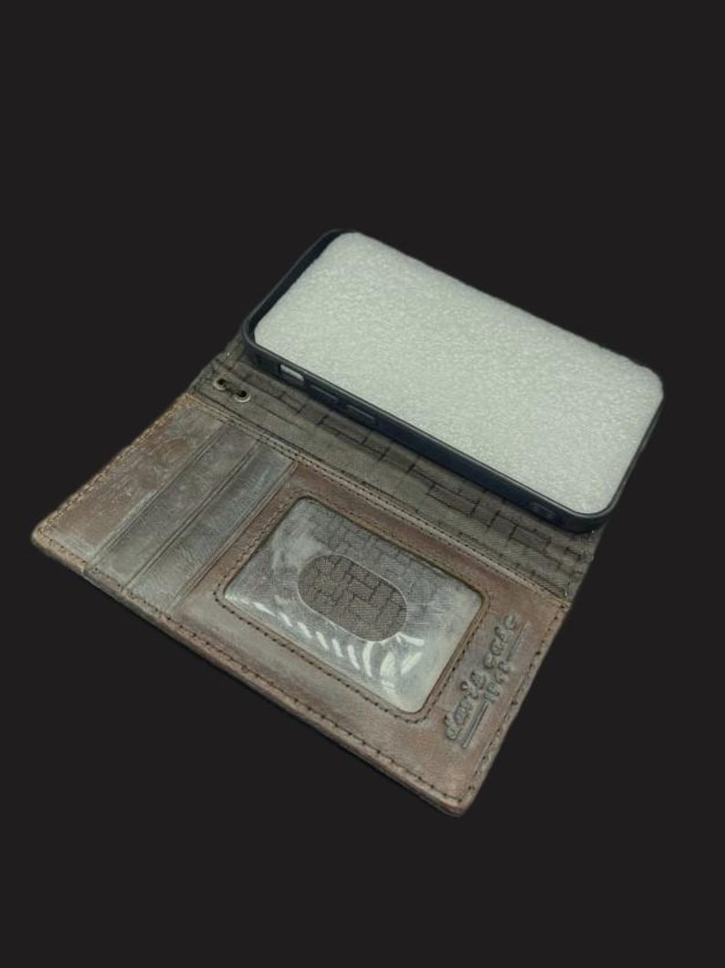 May include: A brown leather phone case with a built-in wallet. The case has a slot for credit cards and a clear window for displaying an ID. The case is open and the phone is not in the case.