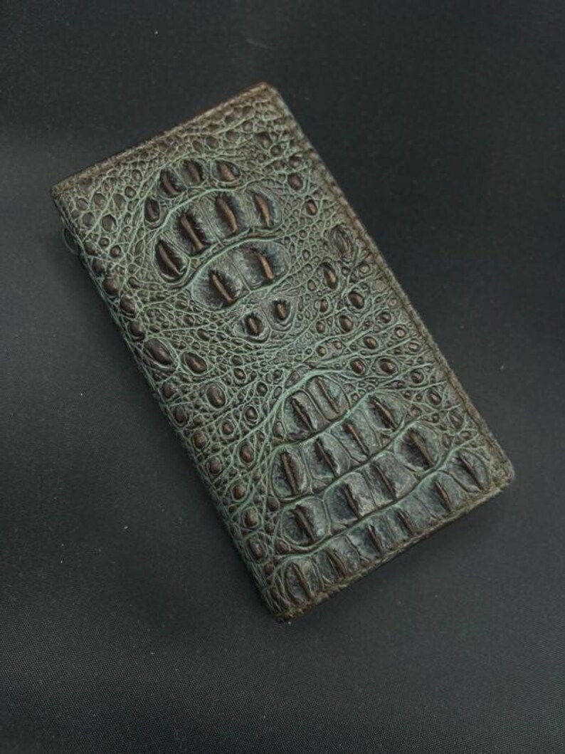 May include: A green alligator skin wallet with a brown embossed pattern.