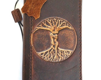 May include: A brown leather journal with a tooled design of a tree of life with two figures embracing. The journal has a leather strap closure and a small leather tag.