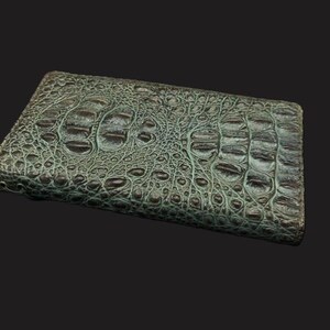 May include: A green alligator skin wallet with a textured surface.