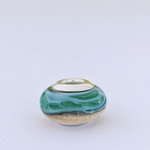 May include: A round glass bead with a green and white marbled design and a gold glitter accent.