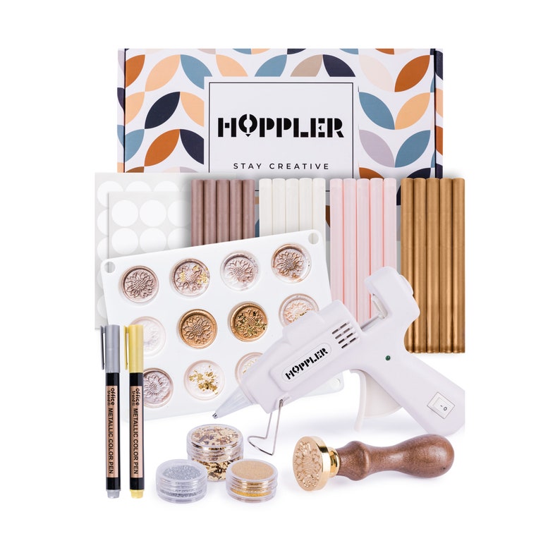 May include: A craft kit with a white glue gun, wax sticks in gold, pink, white, and brown, a silicone mold, two metallic color pens, and a wooden stamp with a gold metal top. The kit is packaged in a box with the text "HOPPLER STAY CREATIVE".