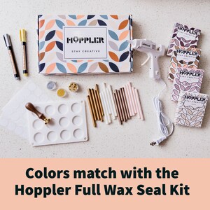 May include: A Hoppler Full Wax Seal Kit with a white glue gun, wax sticks in gold, white, brown, and pink, a silicone mold with 12 circles, a stamp, and a box with the text "Hoppler Stay Creative".