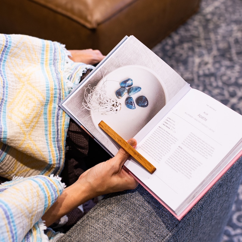 May include: A close-up of a book with a wooden bookmark. The book is open to a page with a photo of blue agate stones in a white bowl. The text on the page reads "Blue Agate".
