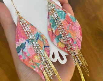 May include: A pair of pink and green floral dangle earrings with gold fringe and clear rhinestone accents. The earrings are on a white background with the text "The Studded Antler".