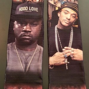 May include: Pair of black socks featuring portraits of two men, with the text "HOOD LOVE" and "The Infamous... MOBB DEEP" in white. The socks have a red and black gradient at the bottom.