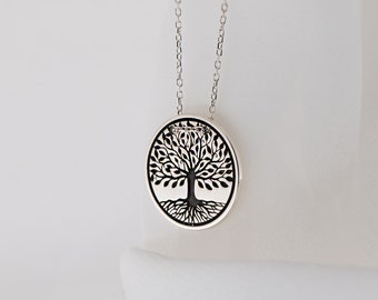 May include: A silver necklace with a round pendant featuring a black tree of life design.