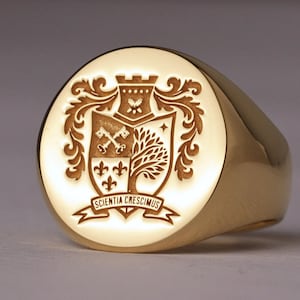 May include: A gold signet ring with an engraved crest. The crest features a shield with keys, a tree, and a star, topped with a castle. The banner below reads "SCIENTIA CRESCIMUS".