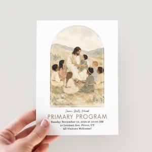 May include: A rectangular programme card featuring a watercolour illustration of a figure with long hair sitting in a field surrounded by children, framed by an arch. Text reads: Seven Hills Ward, PRIMARY PROGRAM, Sunday November 14, 2026 at 10:00 AM, 14 Leeman Ave, Provo, UT, All Visitors Welcome!