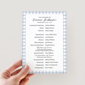 May include: A baptism program with a light blue gingham border. The program lists the details of Emma Anderson's baptism, including the date, participants, and order of service. The text is in a classic serif font.