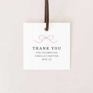 May include: White thank you tag with a pink ribbon bow and the text "Thank You for celebrating Camilla's Baptism with us".