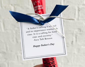 May include: A Father's Day gift featuring two red beef stick packages, a blue ribbon, and a white card. The card has a quote by Ezra Taft Benson and the text "Happy Father's Day."