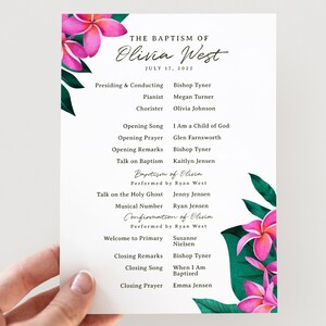 Op de afbeelding: Een wit programma voor een doopceremonie met een bloemenontwerp met roze bloemen en groene bladeren. Het programma geeft de volgorde van de gebeurtenissen weer, inclusief de namen van de voorganger, muzikanten en sprekers. Het programma is getiteld "De doop van Olivia West" en de datum is 17 juli 2022.