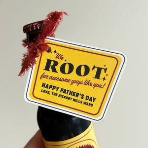May include: A bottle of root beer with a yellow Father's Day gift tag. The tag reads "We ROOT for awesome guys like you! HAPPY FATHER'S DAY LOVE, THE HICKORY MILLS WARD". The tag is tied to the bottle with a red ribbon.