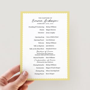 May include: A yellow baptism program with a scalloped edge, held by a hand. The program details Emma Anderson's baptism, including the date, speakers, and musical selections. The text is in a classic, elegant font.
