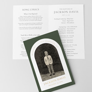 Peut inclure: Une carte d'invitation de baptême avec une photo d'un jeune garçon en costume, encadrée par une arche blanche sur un fond vert foncé. La carte indique "Bienvenue au baptême de Jackson Davis" et la date du 14 novembre 2023. Le livret ouvert affiche des paroles de chansons et des détails du baptême.