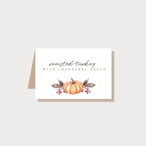 May include: A white card with the text "roasted turkey with cranberry sauce" and a watercolor illustration of an orange pumpkin with brown leaves and red berries.