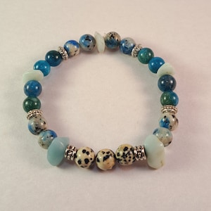 May include: A bracelet made with blue, green, and white stones. The bracelet has silver accents and is made with natural stones.