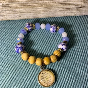 May include: A blue and white beaded bracelet with a wooden charm that says "Yahusha Ha Mashiach is the Way, the Truth and the Life John 14:6".