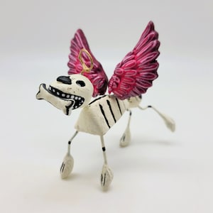 Día de los muertos de arcilla: perro con alas rosas y halo