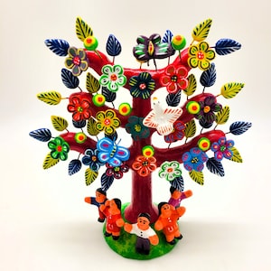 Puede incluir: Una escultura de árbol de cerámica colorida con un tronco rojo, hojas verdes y flores en tonos rojos, amarillos, azules y verdes. Cinco figuras se paran alrededor de la base del árbol.