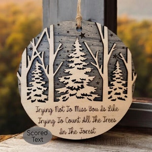 Puede incluir: Un adorno redondo de madera con un diseño de árboles y estrellas cortado con láser. El adorno tiene el texto "Trying Not To Miss You Is Like Trying To Count All The Trees In The Forest" y "Scored Text".