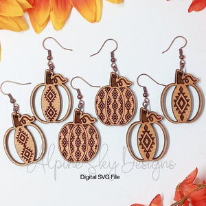 Peut inclure: Cinq paires de boucles d'oreilles en bois en forme de citrouille avec un motif g&eacute;om&eacute;trique. Les boucles d'oreilles sont brunes avec un crochet de couleur cuivre.