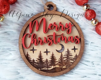 May include: A wooden Christmas ornament with a red "Merry Christmas" inscription and a silhouette of a forest scene with trees, a crescent moon, and stars.