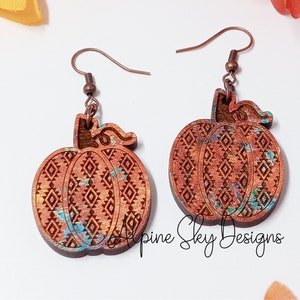 Peut inclure: Une paire de boucles d'oreilles en bois en forme de citrouille avec un crochet en fil de cuivre. Les citrouilles sont peintes avec un motif marbr&eacute; brun, orange et bleu et ont un motif g&eacute;om&eacute;trique grav&eacute; &agrave; la surface. Les boucles d'oreilles sont &eacute;tiquet&eacute;es "Alpine Sky Designs".