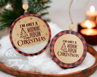 Puede incluir: Dos adornos navideños redondos con un diseño de cuadros de búfalo rojo y negro. Los adornos son de madera y tienen un fondo dorado con el texto "Solo soy una persona de la mañana en Navidad" en rojo.