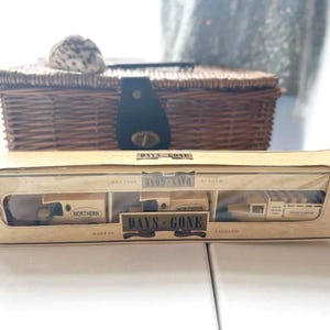 May include: A Days Gone model train set in its original packaging, with the text "Days Gone" and "Northern". The box is tan with clear windows, displaying the miniature trains. A wicker basket and seashell are in the background.