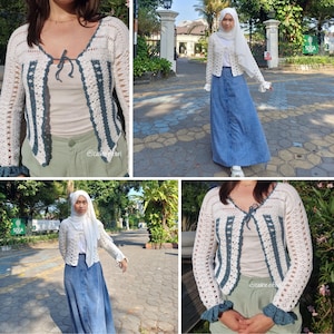 May include: A white crochet cardigan with dark teal accents and a tie closure. The cardigan features a V-neck and long sleeves with ruffled cuffs. The design includes vertical teal stripes and a scalloped trim.