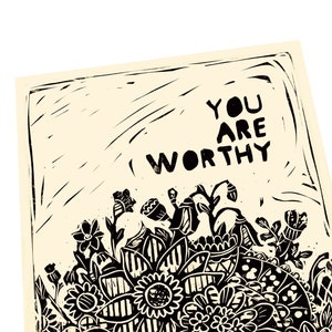 May include: Black and white linocut print with a floral design and the text "You are worthy".