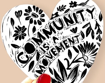 Może przedstawiać: Czarno-biała naklejka w kształcie serca z tekstem "Community is a Movement" i wzorami kwiatowymi.