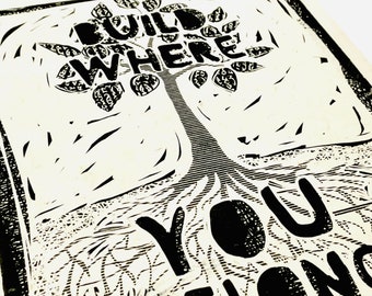 May include: Black and white print of a tree with the words "Build Wild Where You Belong" printed on it.