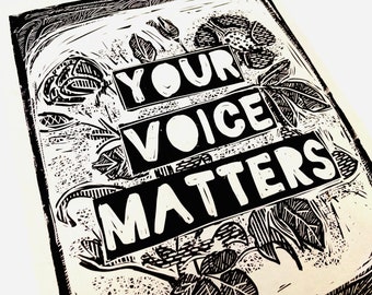 May include: Black and white linocut print with the text "Your Voice Matters" surrounded by stylized floral designs.