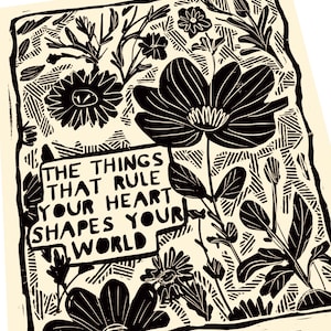 May include: Black and white linocut print with a floral design and the text "The things that rule your heart shapes your world".