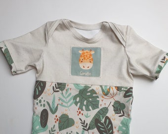 May include: A cream-coloured baby onesie with short sleeves features a green, brown and orange jungle-themed print. The onesie has a patch on the chest with a cartoon giraffe and the word "Giraffe".