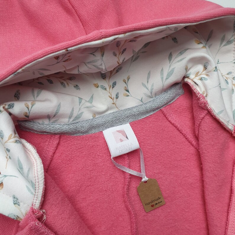 Peut inclure: Sweat-shirt &agrave; capuche rose avec une doublure &agrave; imprim&eacute; floral. Le sweat-shirt a une fermeture &eacute;clair et une petite &eacute;tiquette qui dit "Fait main avec amour".