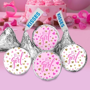 May include: Pink and gold 'It's a Girl' favor tags with hearts on silver foil wrapped chocolate kisses.