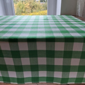May include: Green and white checkered tablecloth. The tablecloth is made of a woven fabric and has a smooth texture.