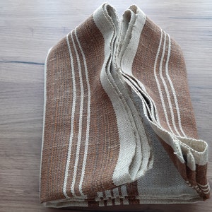 May include: A folded brown and white striped fabric towel. The towel is folded in half and then folded again, creating a rectangular shape.