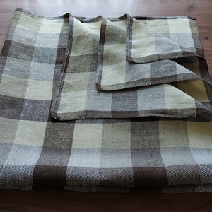 May include: A set of three folded linen napkins in a brown and cream plaid pattern.