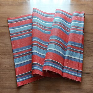 May include: Red and blue striped table runner with a woven texture.