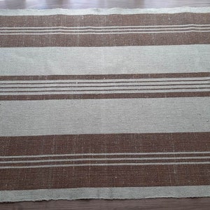 May include: A brown and beige striped fabric with a woven texture. The fabric has a subtle sheen and is perfect for a variety of home decor projects.