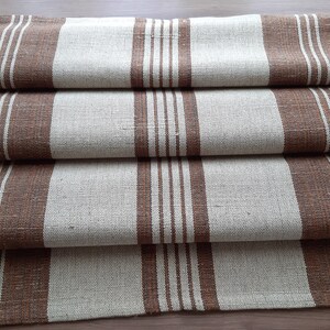 May include: A folded brown and white striped linen table runner. The runner has a subtle texture and is made of natural fibres.