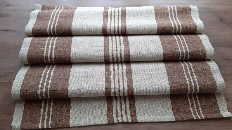 May include: A folded brown and white striped linen table runner. The runner has a subtle texture and is made of natural fibres.