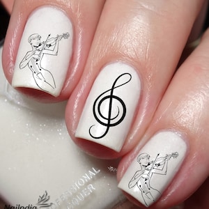 May include: White nail polish with black nail art designs. One nail has a treble clef, and two nails have a black and white illustration of a person playing a violin.